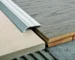 Close-up of metal edge trim laid over plywood and subfloor panels during floor installation. PROFILITEC picuratoare plinte coltare terminatii profile profesionale