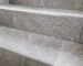Gray granite stairs with textured surfaces and slim metal edge trim along the treads